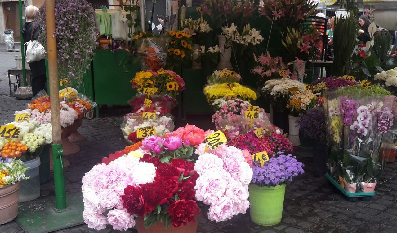 Eimer mit zahlreichen bunten Schnittblumen stehen auf einem Marktplatz.